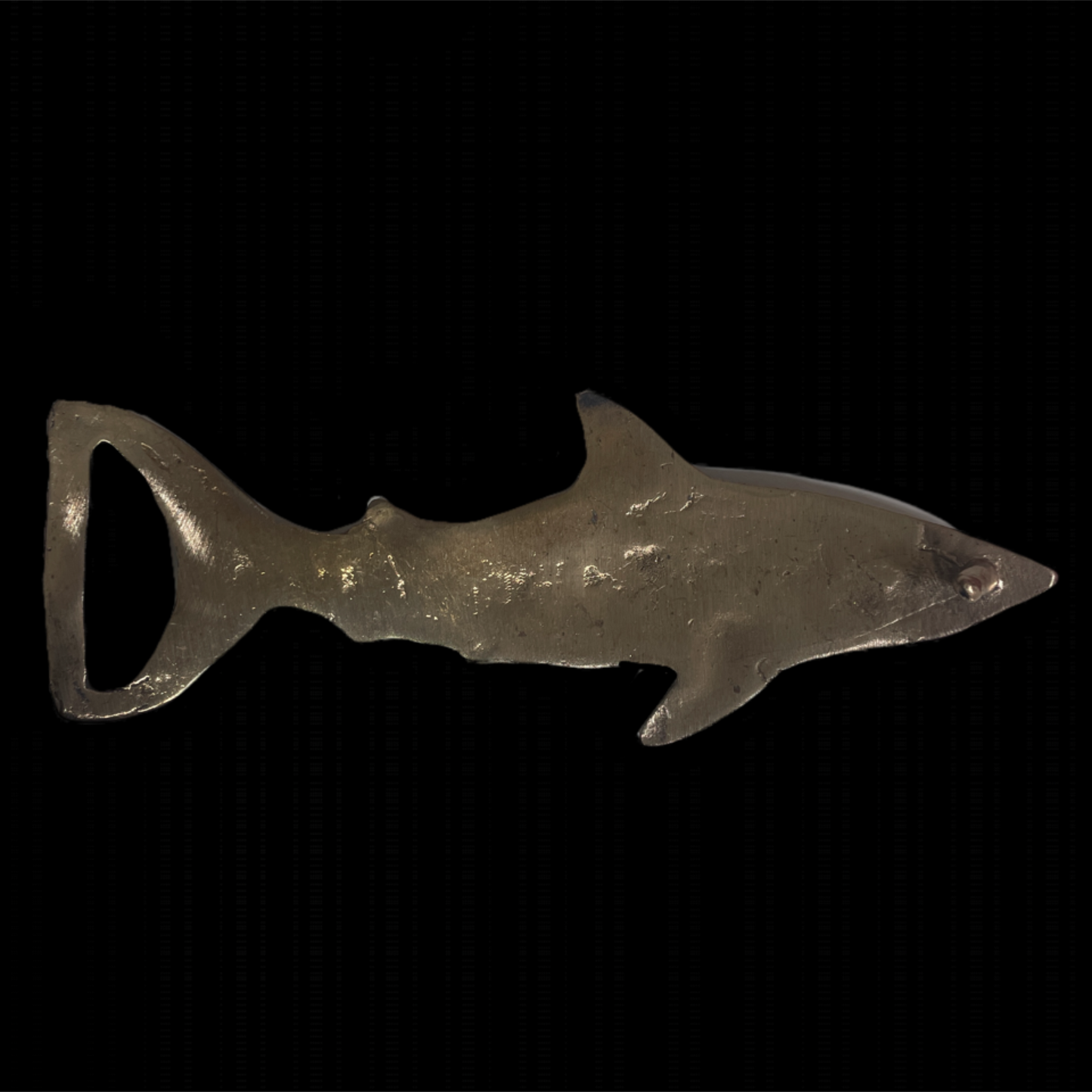 Metal shark-shaped bottle opener on a black background