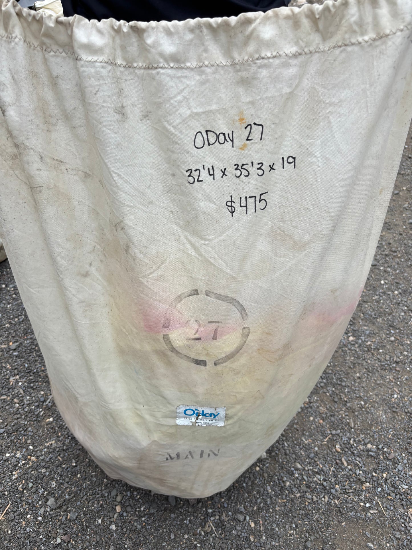 White sandbag with text and a target symbol on a concrete surface