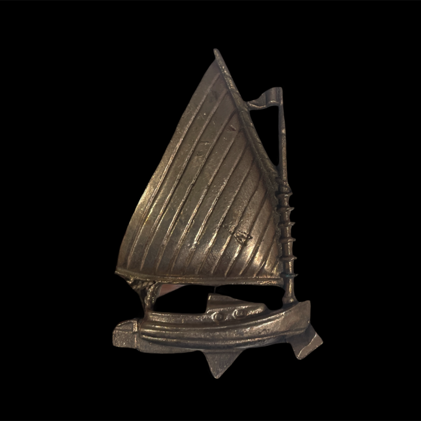 Metallic sailboat figurine on a black background