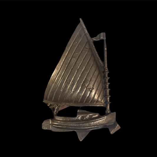 Metallic sailboat figurine on a black background