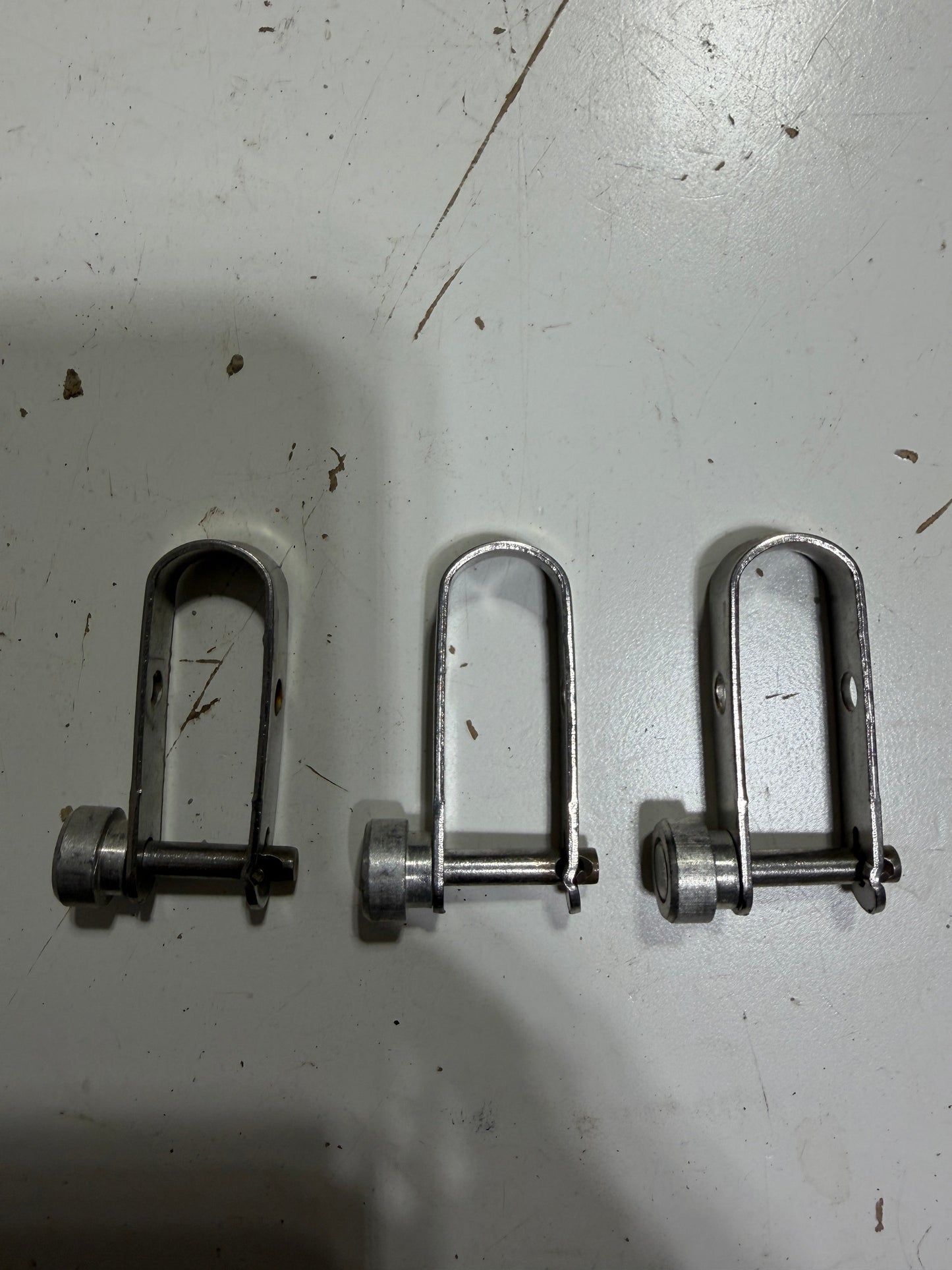 Three metal U-bolts on a white surface with visible shadows.