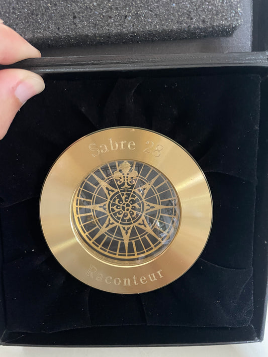 Gold circular object with intricate design on a black velvet background