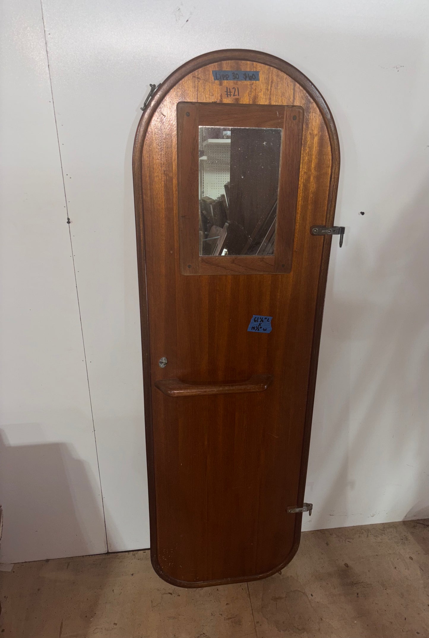 Wooden door with a mirror on a white wall