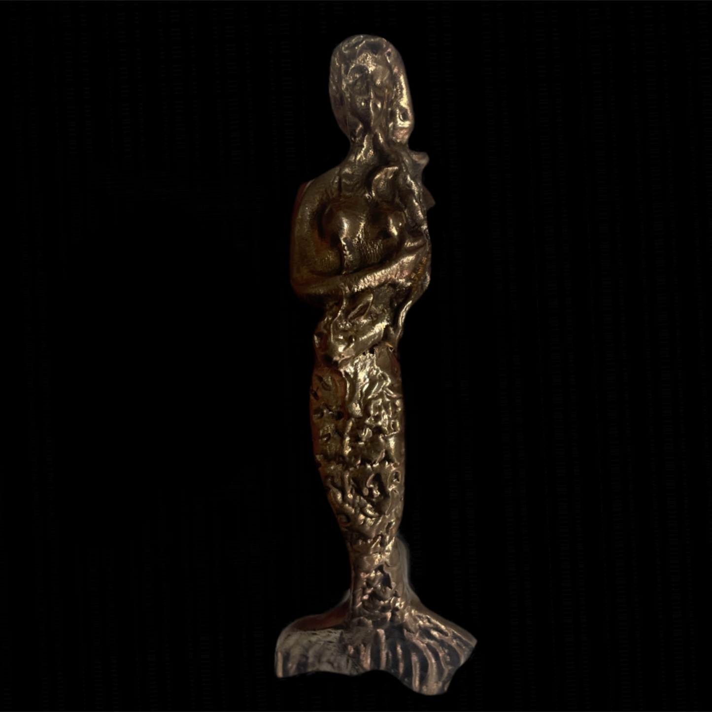 Bronze mermaid figurine on a black background