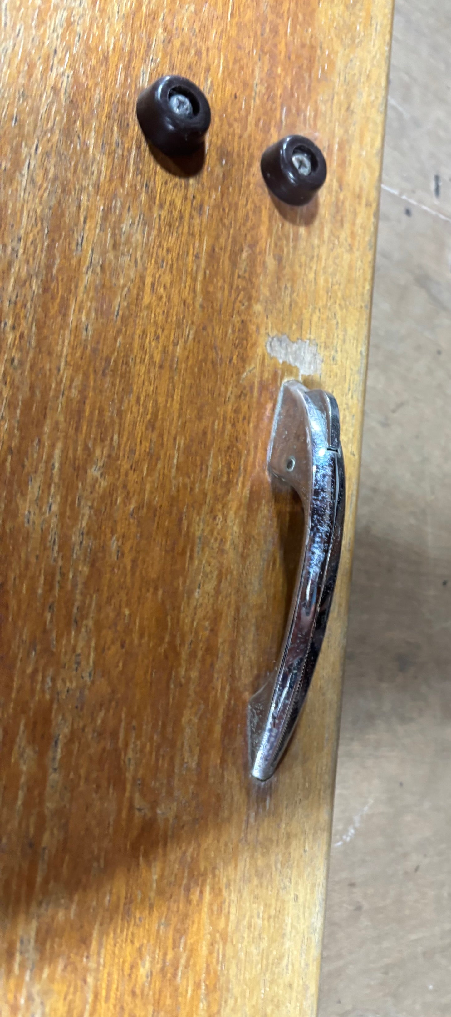 Wooden surface with a metal handle and two black knobs.