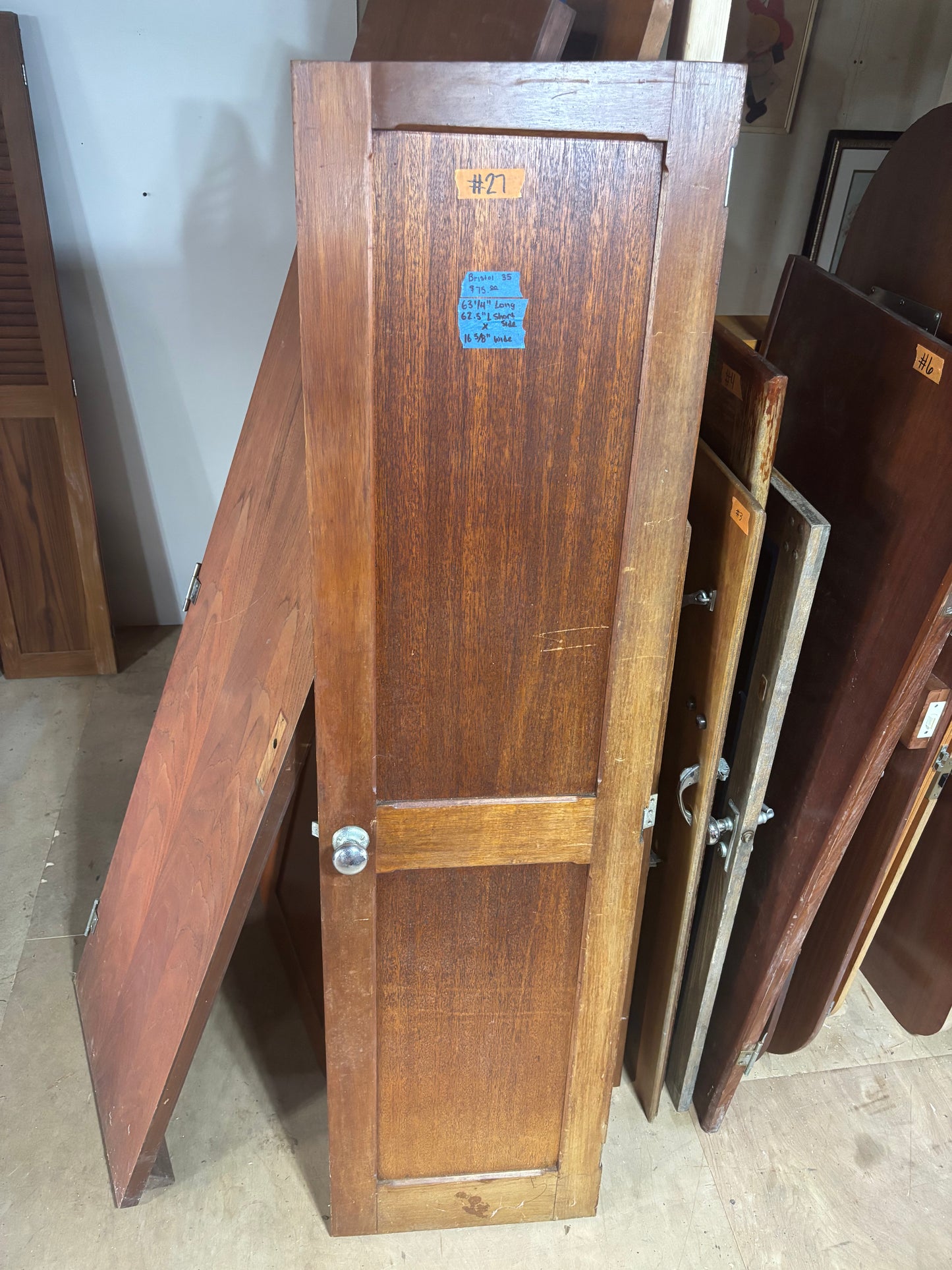 Wooden cabinet doors with a visible number tag on a floor.