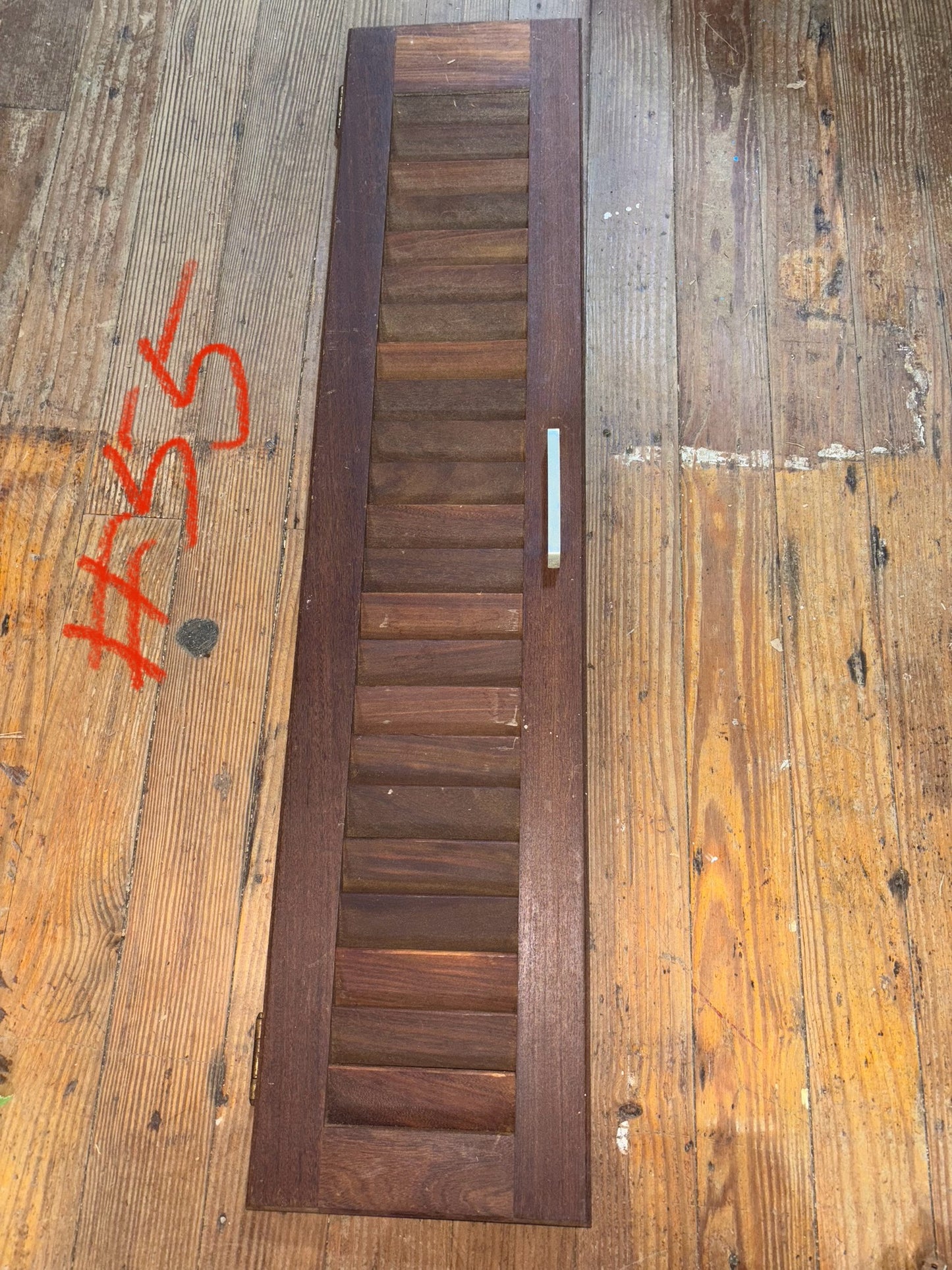 Wooden shutter on a wooden surface with visible wear and graffiti.