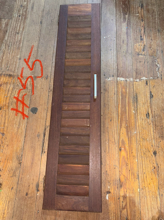 Wooden shutter on a wooden surface with visible wear and graffiti.