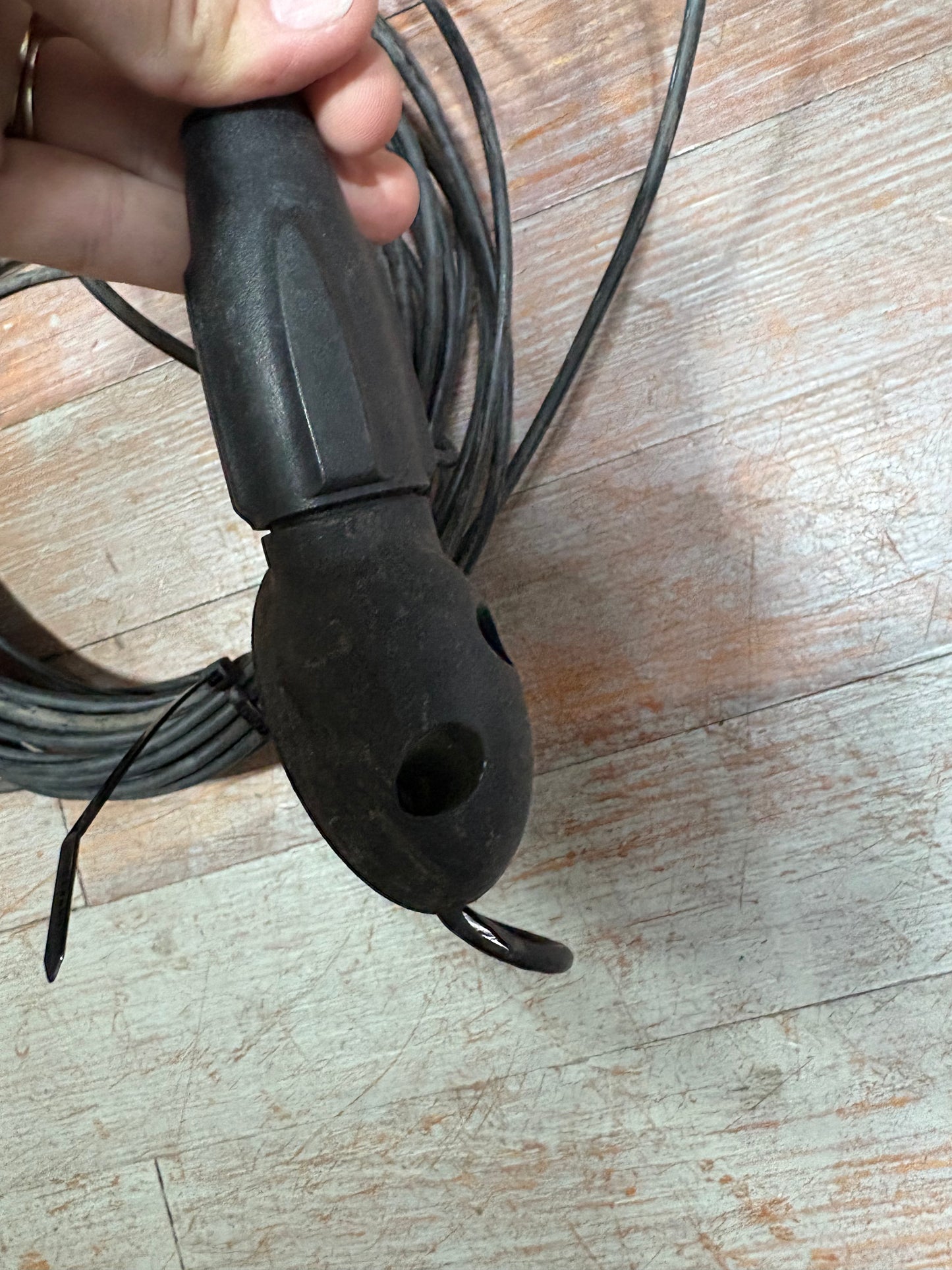 Black cable connector held by a hand on a wooden surface