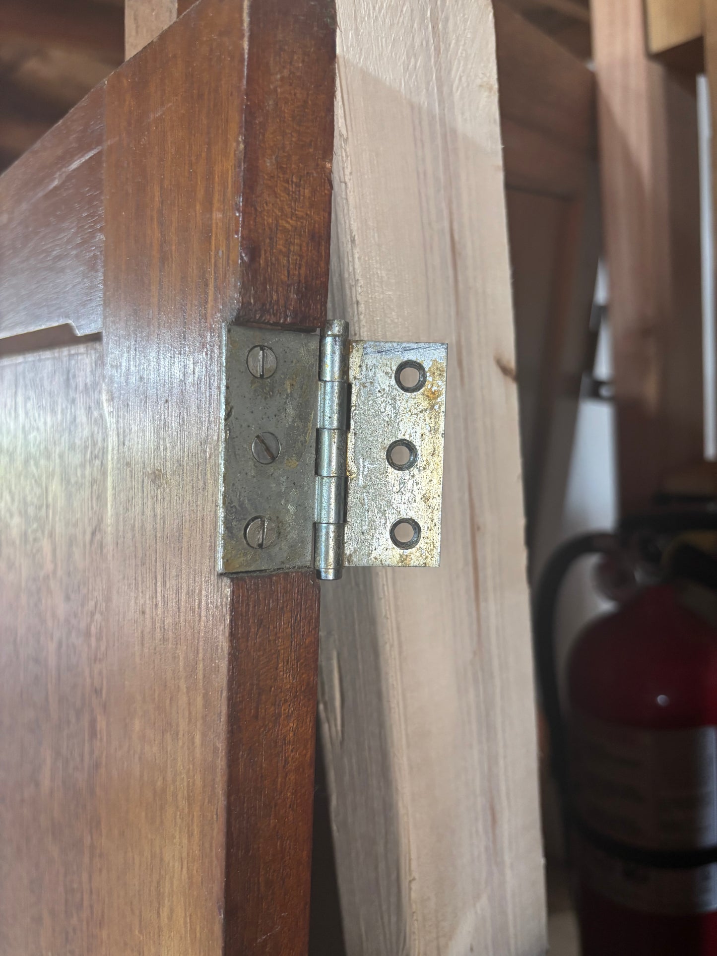 Close-up of a wooden door with a metal hinge, blurred background