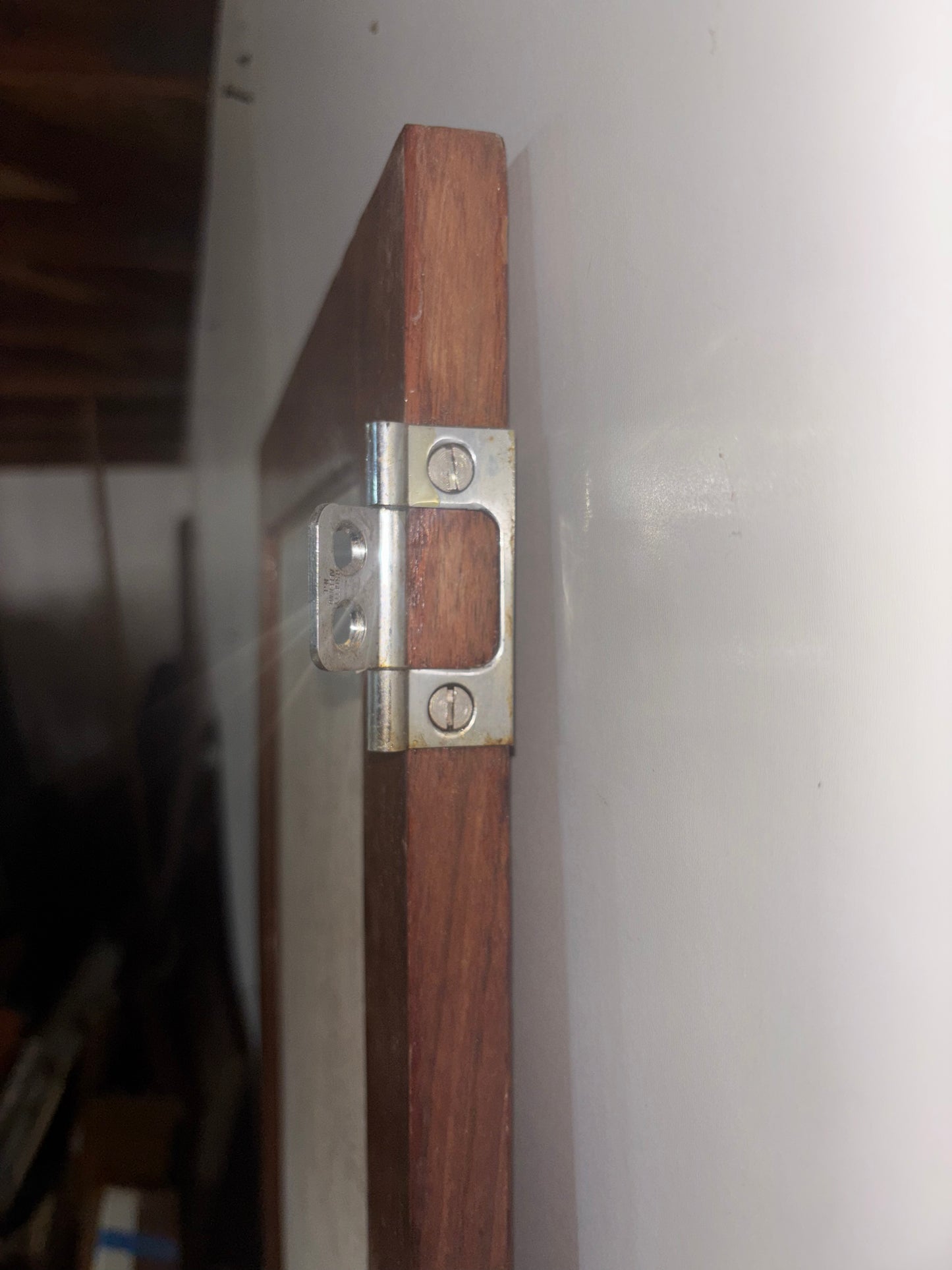 Wooden door with metal hinge on a white wall