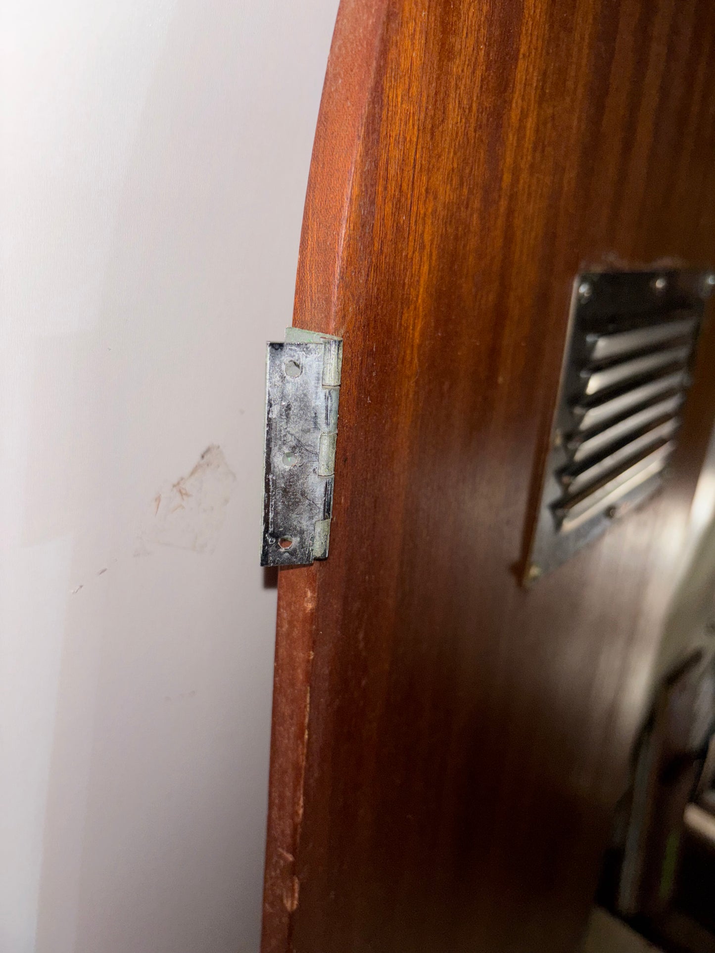 Wooden door with a metal handle and lock on a white wall.