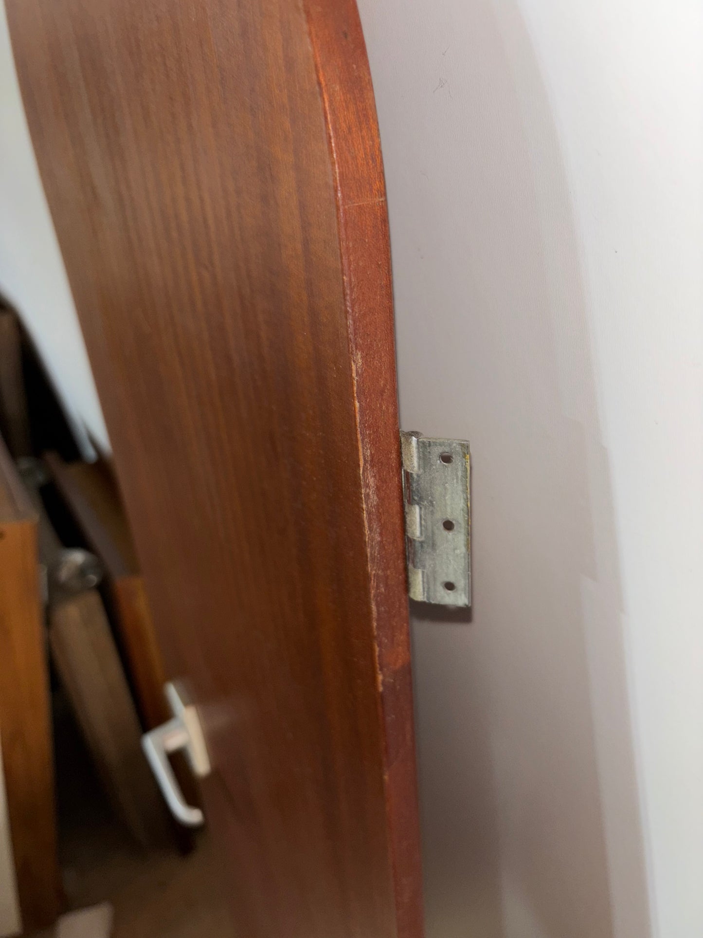 Wooden door with a metal hinge on a white wall