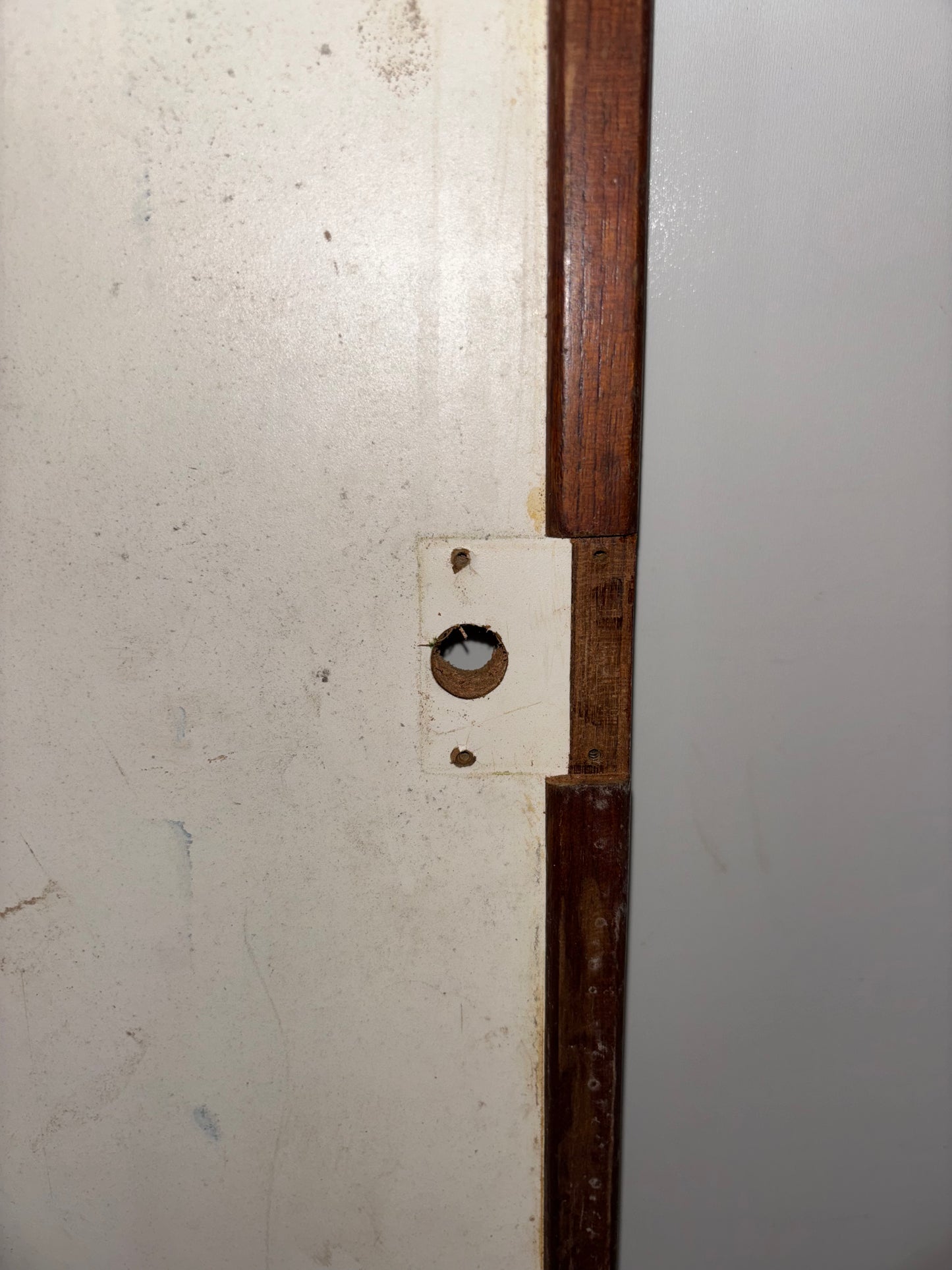 Close-up of a wooden frame with a metal bracket on a white wall.