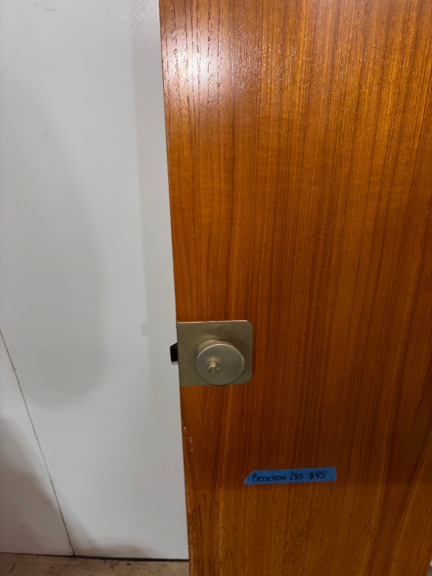 Wooden door with a metallic lock and white wall in the background