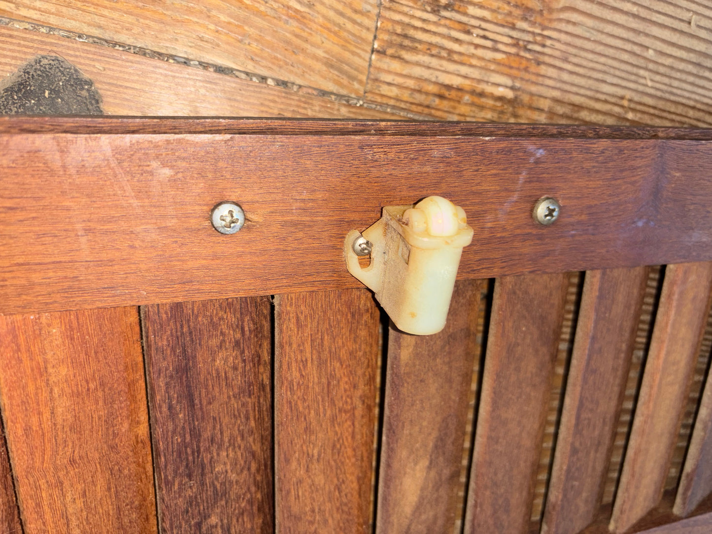 Wooden slat with a metal bracket and screw on a wooden surface