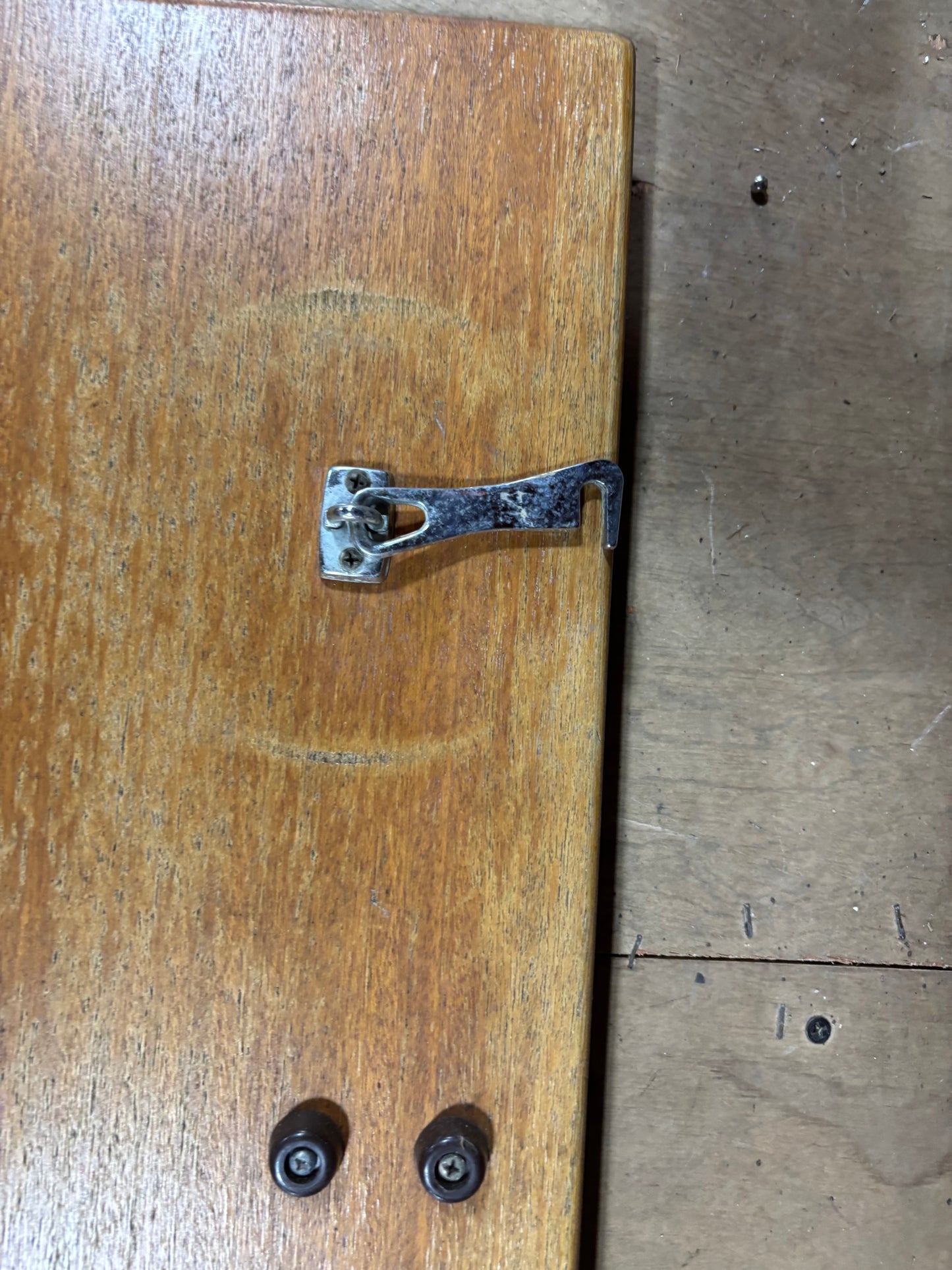 Metal latch on a wooden door with a wooden floor in the background