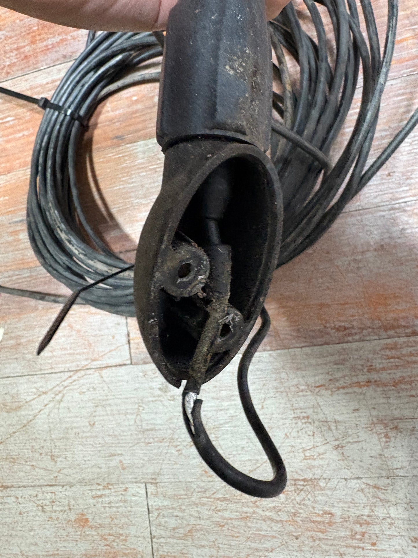 Coiled black cable with a metal clip on a wooden surface