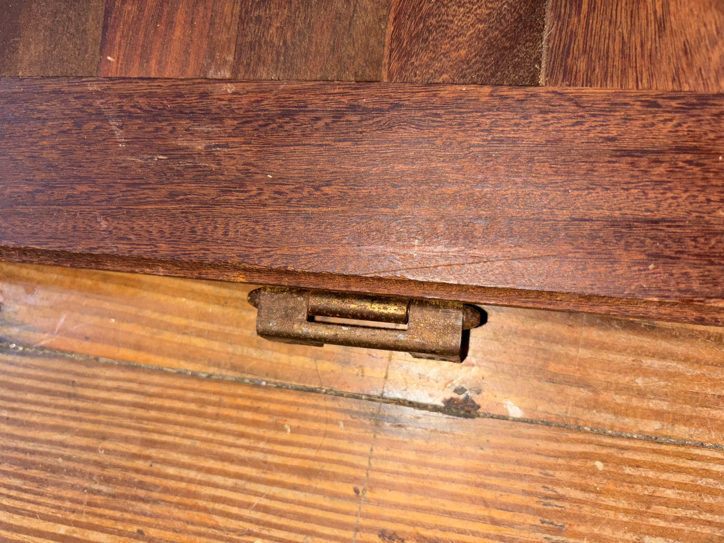 Close-up of a wooden surface with a metal hinge