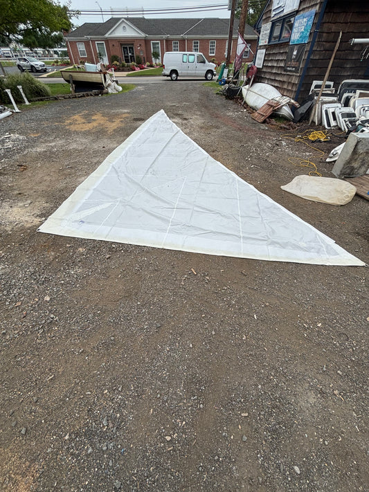 White triangular fabric on a gravel surface with a building and chairs in the background