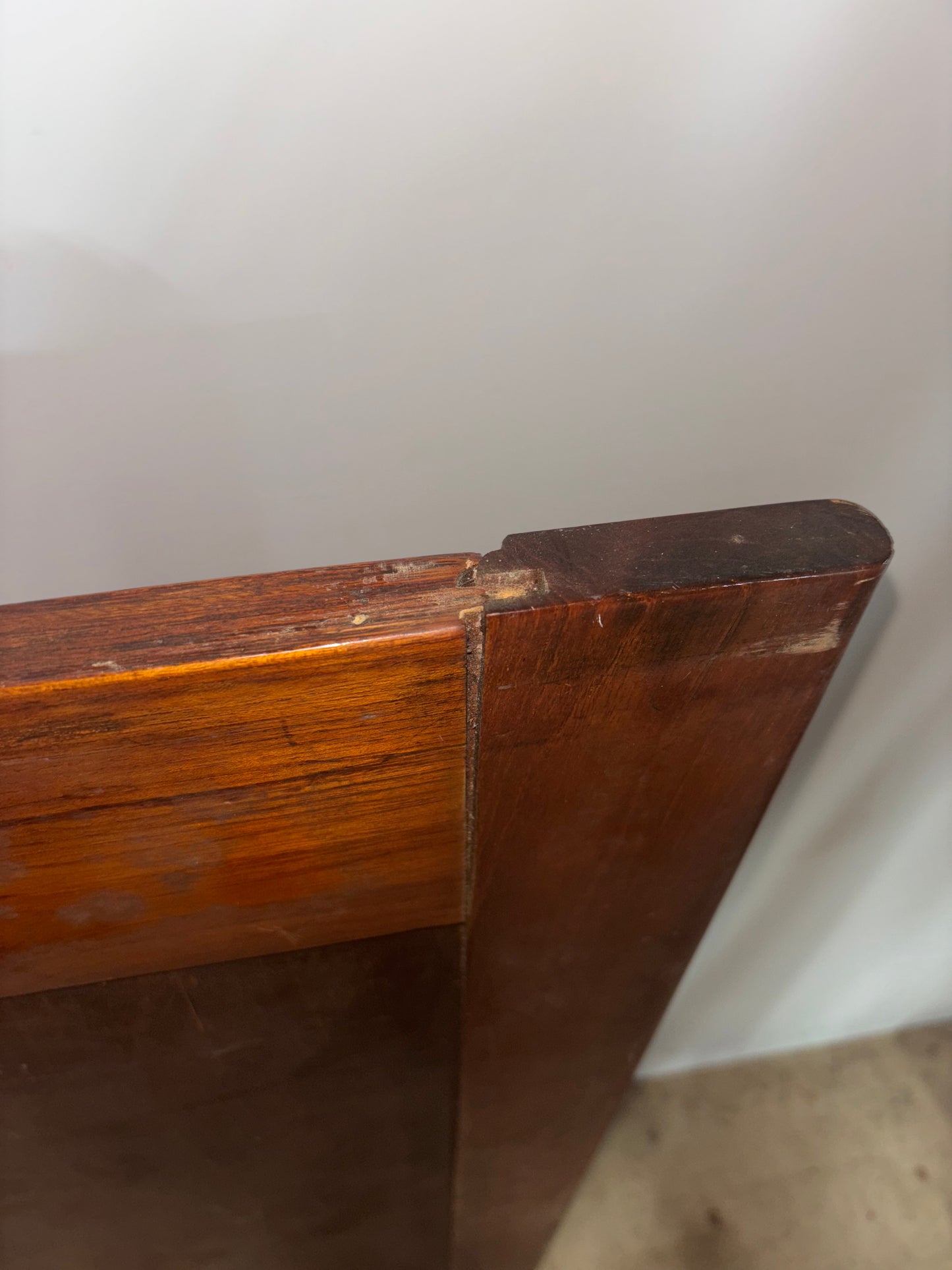 Close-up of a wooden surface with a visible joint against a white wall.