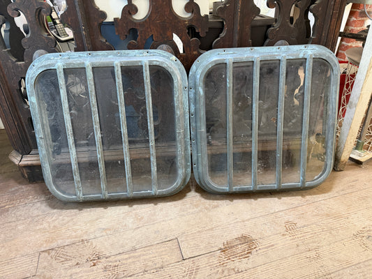 Two bronze hatches on a wooden floor with decorative elements in the background.